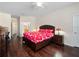 Main bedroom with dark wood floors and bold floral bedding, offering natural light and attached bathroom at 26812 Augusta Springs Cir, Leesburg, FL 34748