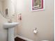Powder room with pedestal sink, oval mirror, and dark laminate floors, accented by tastefully framed art at 26812 Augusta Springs Cir, Leesburg, FL 34748