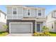 Two-story house with gray siding, stone accents, and a two-car garage at 3937 Lana Ave, Davenport, FL 33897