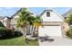 Charming two-story home featuring a well-manicured lawn, a brick-paved driveway, and lovely palm trees at 1108 Darnaby Way, Orlando, FL 32824