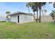 A detached white garage sits on a green lawn near palm trees and a fence at 718 N Grandview Ave, Daytona Beach, FL 32118