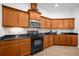 Kitchen with brown cabinetry, black appliances, granite countertops, and tile backsplash at 164 Pergola Pl, Ormond Beach, FL 32174