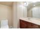 A well-lit powder room featuring a cherry wood vanity, large mirror and patterned wallpaper at 1712 Whitney Isles Dr, Windermere, FL 34786