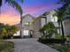Majestic two-story home showcasing manicured landscaping, a paver driveway, and a welcoming entrance with an arched doorway at 1712 Whitney Isles Dr, Windermere, FL 34786