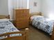 Bedroom with two twin beds, a wood dresser, and blue and white bedding at 603 Keppel Ct, Kissimmee, FL 34746