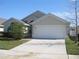 Front view of a single-story house with a white garage door and manicured lawn at 603 Keppel Ct, Kissimmee, FL 34746