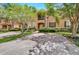 Two-story townhome with a landscaped front yard, brick paver driveway, and palm trees at 120 Palermo St, Davenport, FL 33897