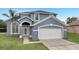Two-story house with gray exterior, white garage door, and green lawn at 2556 Volta Cir, Kissimmee, FL 34746