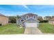 Two-story house with gray siding, two-car garage, and a palm tree at 2556 Volta Cir, Kissimmee, FL 34746