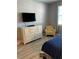 Cozy bedroom featuring wood flooring, dresser with TV, and a comfortable yellow chair at 3006 Bonfire Beach Dr # 102, Kissimmee, FL 34746