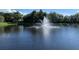 Scenic pond with a central water fountain feature surrounded by lush trees and a clear sky at 3006 Bonfire Beach Dr # 102, Kissimmee, FL 34746