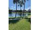 Lakeside view with clear water, bordered by lush green grass and palm trees at 3006 Bonfire Beach Dr # 102, Kissimmee, FL 34746