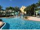 Exterior view of community pool with splash fountains, palm trees, and colorful buildings in the background at 3006 Bonfire Beach Dr # 102, Kissimmee, FL 34746