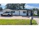 White house with teal accents, paver driveway, and vehicle parked in front at 5958 Lawnview Dr, Orlando, FL 32812