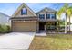 Charming two-story home with a stone facade, attached two-car garage, and manicured front lawn at 1624 Valmont Ln, Apopka, FL 32703