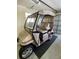 Tan golf cart with beige top parked in garage at 2530 Saffron Ln, The Villages, FL 32162