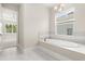 Bright bathroom with a tub, a view of an outdoor landscape, and neutral tiling at 7399 Gathering Ct, Reunion, FL 34747