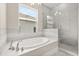 Bright bathroom with a tub, a shower enclosed with glass, and neutral tiling at 7399 Gathering Ct, Reunion, FL 34747