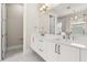 Bright bathroom features a double vanity with white cabinetry and a large mirror at 7399 Gathering Ct, Reunion, FL 34747
