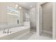 Bright bathroom with a tub, a shower enclosed with glass, and neutral tiling at 7399 Gathering Ct, Reunion, FL 34747