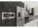 Modern kitchen featuring stainless steel appliances, dark cabinets, and stylish backsplash at 7399 Gathering Ct, Reunion, FL 34747