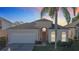 Tan house with a two-car garage, palm tree, and manicured lawn at 8030 King Palm Cir, Kissimmee, FL 34747