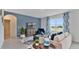 Living room with beige sofa, blue accent chair, and patterned curtains at 1261 Limbali St, Mount Dora, FL 32757