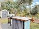 A unique outdoor kitchen with a sink, grill, and a decorative blue facade, sits in a lush backyard at 2122 King Richards Ct, Orange City, FL 32763