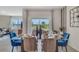 Bright dining room with glass table and blue chairs, looking out to backyard at 7110 Painted Bunting Way, Saint Cloud, FL 34773