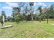 Large backyard with grassy lawn, mature trees, and wooden fence at 1437 Pecos Dr, Ormond Beach, FL 32174