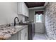 Bright laundry room with granite countertops, white cabinets, and stone accent wall at 1437 Pecos Dr, Ormond Beach, FL 32174