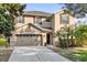 Two-story house with tan siding, brown accents, and a two-car garage at 20811 Sullivan Ranch Blvd, Mount Dora, FL 32757