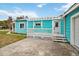 Charming turquoise home featuring a white porch and an attached garage, offering ample parking at 211 Indiana Ave, St Cloud, FL 34769