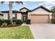 House with a two-car garage, brick driveway, and palm trees at 672 Cordoba Dr, Davenport, FL 33837