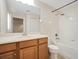 Bright bathroom featuring a wood vanity, mirror, and a shower-tub combo with white tile surround at 9025 Savannah Julip Ln, Orlando, FL 32832