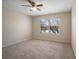 Bright bedroom with a ceiling fan, neutral walls, plush carpeting, and a window overlooking large tree at 9025 Savannah Julip Ln, Orlando, FL 32832
