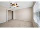 A bright bedroom with a ceiling fan, neutral walls, plush carpeting, closet, and window at 9025 Savannah Julip Ln, Orlando, FL 32832