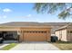 Exterior shot of home featuring a two-car garage, with a well-maintained lawn at 9025 Savannah Julip Ln, Orlando, FL 32832