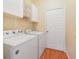 Functional laundry room with white washer and dryer, overhead cabinets, and wood-look floors at 2961 Cedar Glen Pl, Oviedo, FL 32765