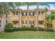 Two-story townhome with yellow exterior, lush landscaping, and palm trees at 8451 Leatherleaf Ln, Orlando, FL 32827