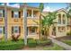 Side view of two-story townhome with yellow painted walls, lush landscaping, and palm trees at 8451 Leatherleaf Ln, Orlando, FL 32827
