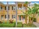 Front view of two story townhome with yellow painted walls, palm trees, and manicured hedges at 8451 Leatherleaf Ln, Orlando, FL 32827