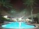Community pool at night with palm trees surrounding at 12021 Villanova Dr # 111, Orlando, FL 32837