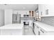 Modern white kitchen with stainless steel appliances and gray backsplash at 37 Hickory Track Way, Ocala, FL 34472
