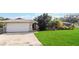 Front view of house with stone exterior, attached garage, and large lawn at 1429 Royal Palm Dr, Edgewater, FL 32132