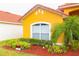 Front view of a yellow house with red tile roof and landscaping at 308 Robin Rd, Davenport, FL 33896