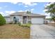 Tan one-story house with gray door, attached garage, and landscaping at 430 Magpie Ct, Kissimmee, FL 34759