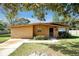 Tan brick ranch home with a landscaped lawn and driveway at 112 Azalea Ln, Sanford, FL 32773