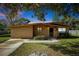 Tan brick ranch home with a landscaped lawn and driveway at 112 Azalea Ln, Sanford, FL 32773