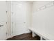 Bright mudroom features coat hooks, a white bench and dark wood-look tile flooring by the exterior door at 13200 Faro Ct # 44, Winter Garden, FL 34787